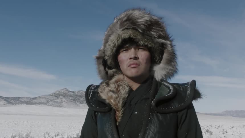 Man in fur coat standing in snow covered pasture