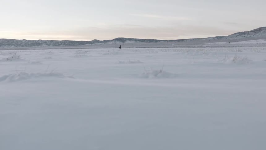 A man who rides a horse through the snow in front of the mountains