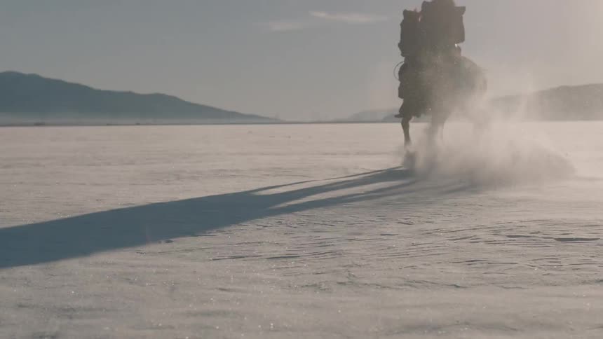Man riding a horse across a snow covered pasture