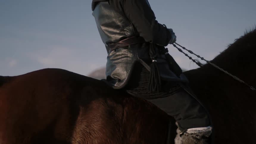 A horseback rider slowly passes a snow covered field