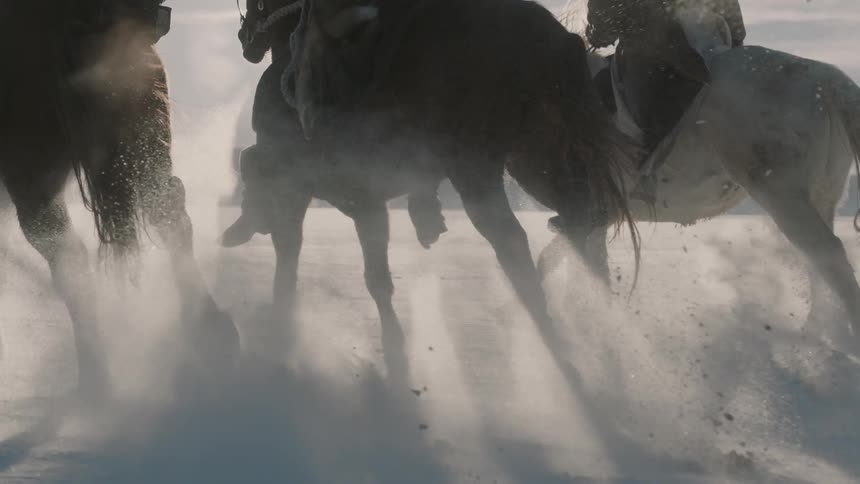 Men riding horses in slow motion in the snow