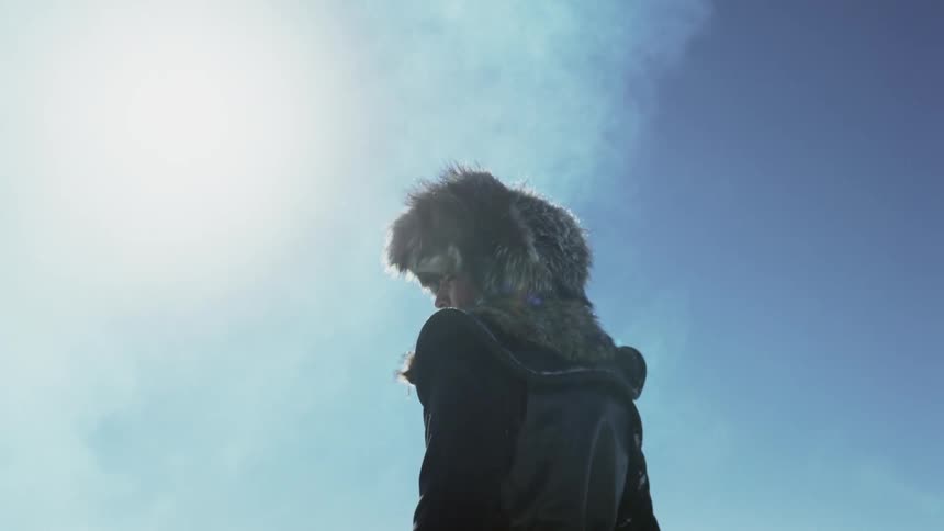 A person in mongolian-type clothing stands in an icy landscape