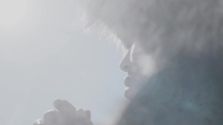 A man wearing a fur hat moves his hand away from his face