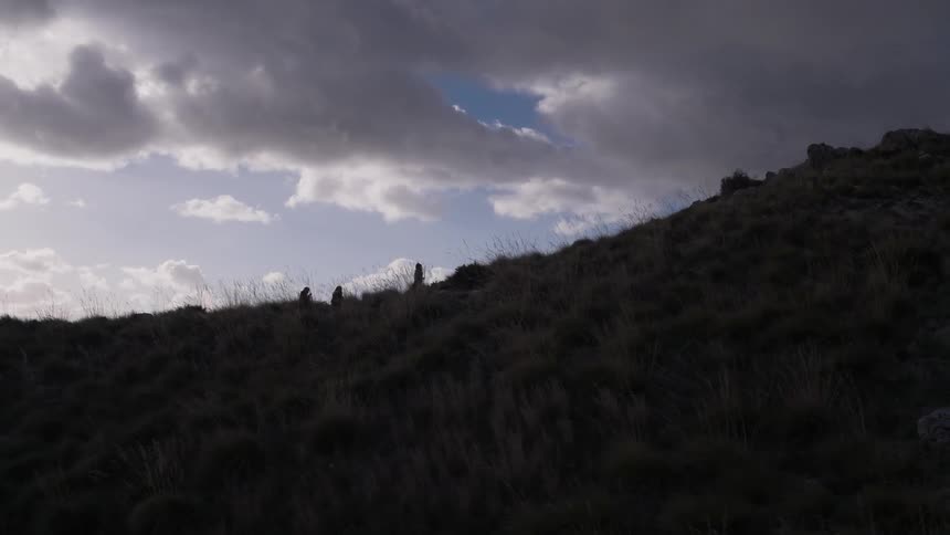 Three men walk on a hillside at dusk