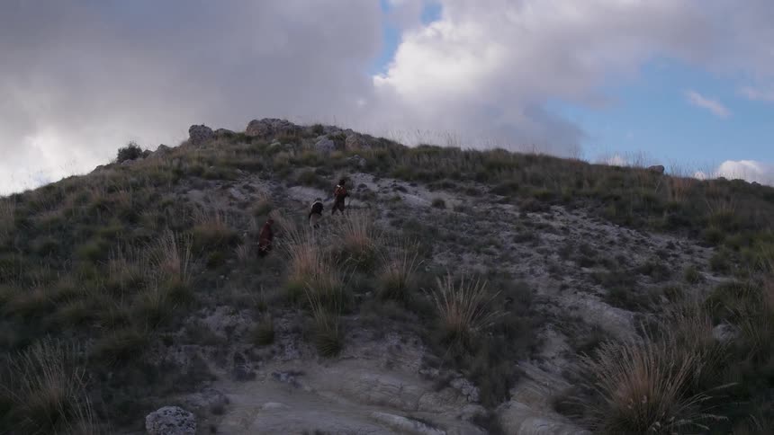 People walk up a hillside on a cloudy evening