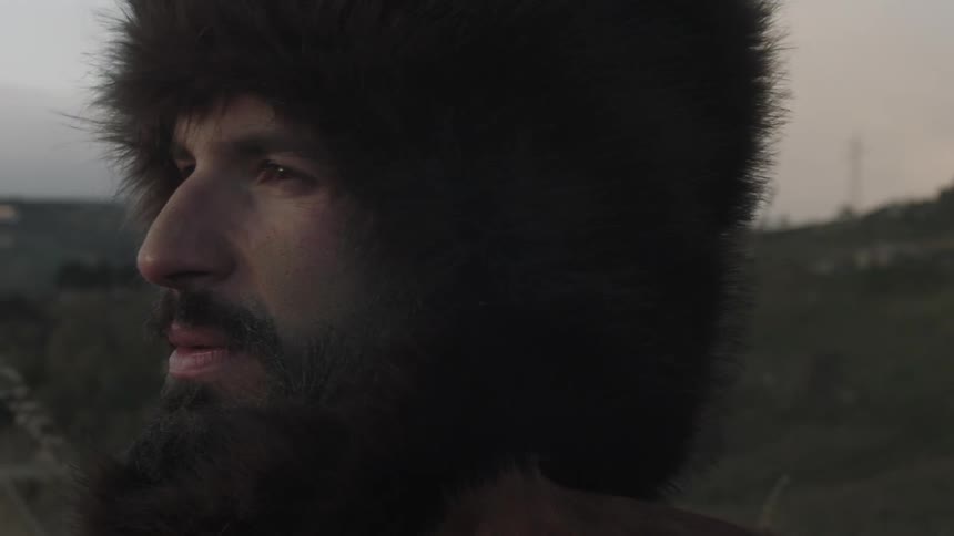 A man wearing a fur hat smiles