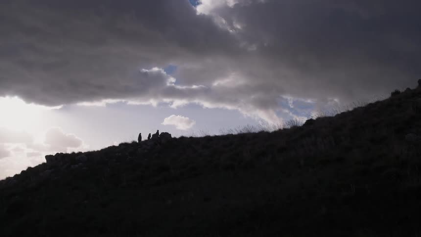 People hiking up a hill on a cloudy day