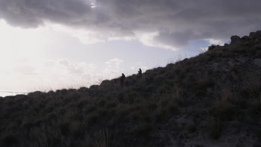 People descending a hill on a cloudy day