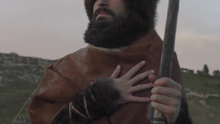 An explorer stands with his hand over his heart