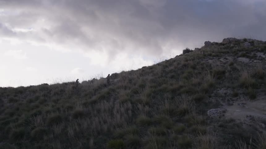 People are climbing up a hill on a cloudy day
