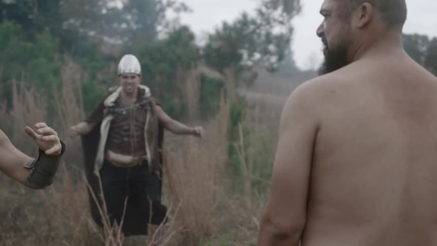 Two men fight while people form a circle around them and egg them on