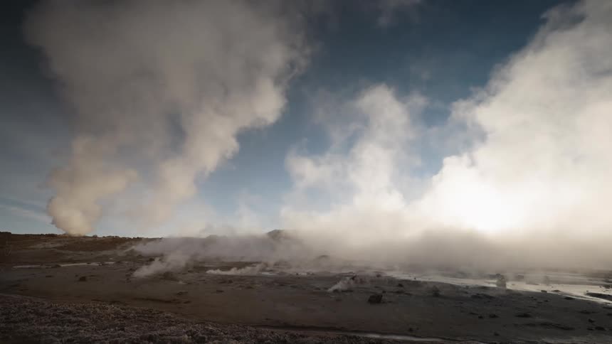Smoke rises from geysers scattered throughout a field