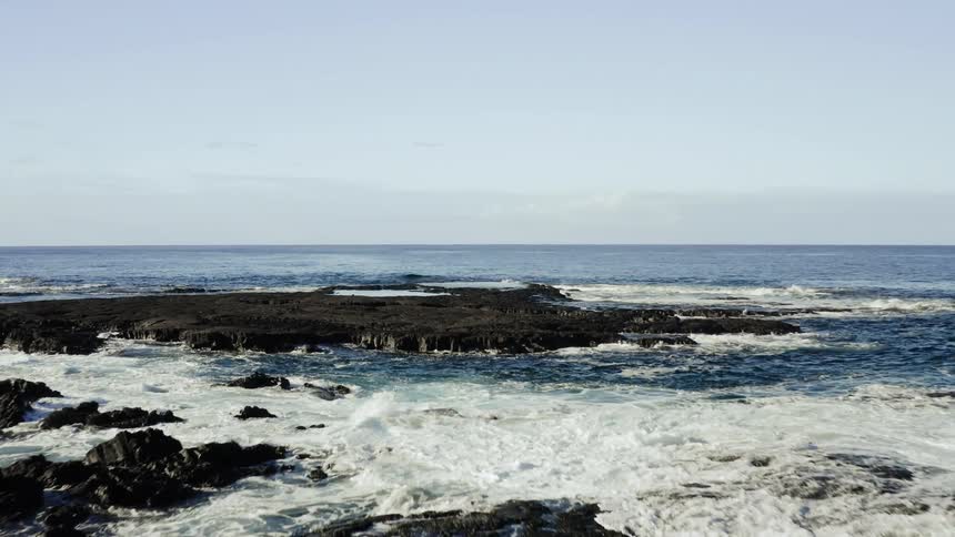 Sea waves crash onto rocks along the vast coast
