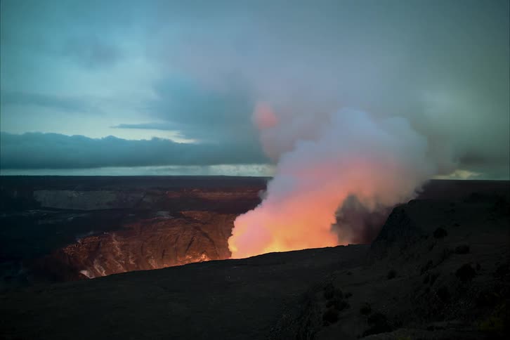 Smoke and flame billowing and glowing in a volcanic crater
