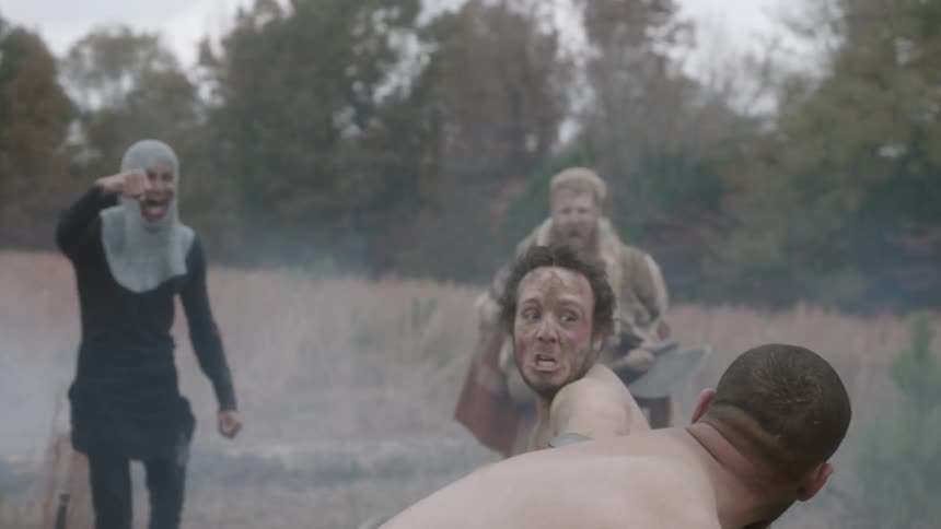 Two men fight while people form a circle around them and egg them on