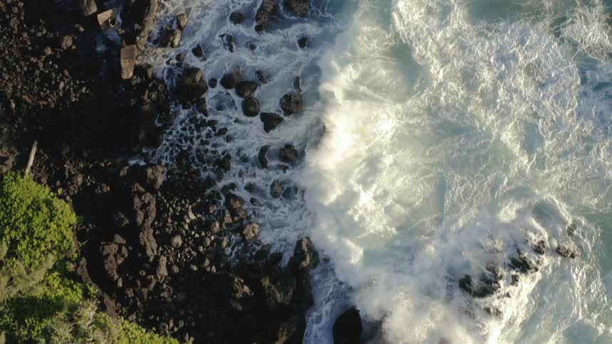 Waves crash onto the shore below a cliff