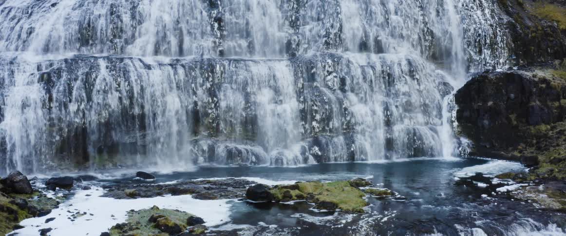 Aerial view of a wide waterfall streaming down the rocky slopes of a mountain