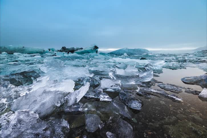 Water bobs slightly as floating ice in the background and vehicle move over water