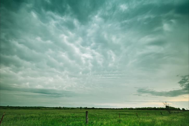 Dark clouds move over a vast fenced in field