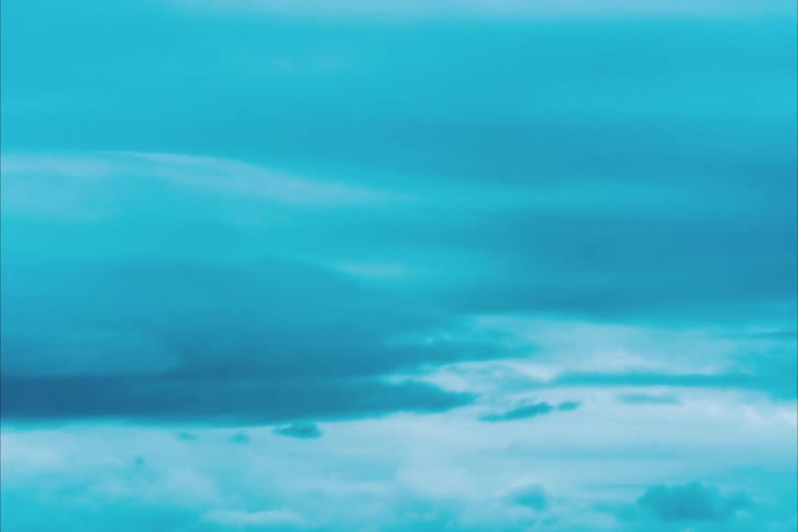 Clouds grow and move across a blue sky