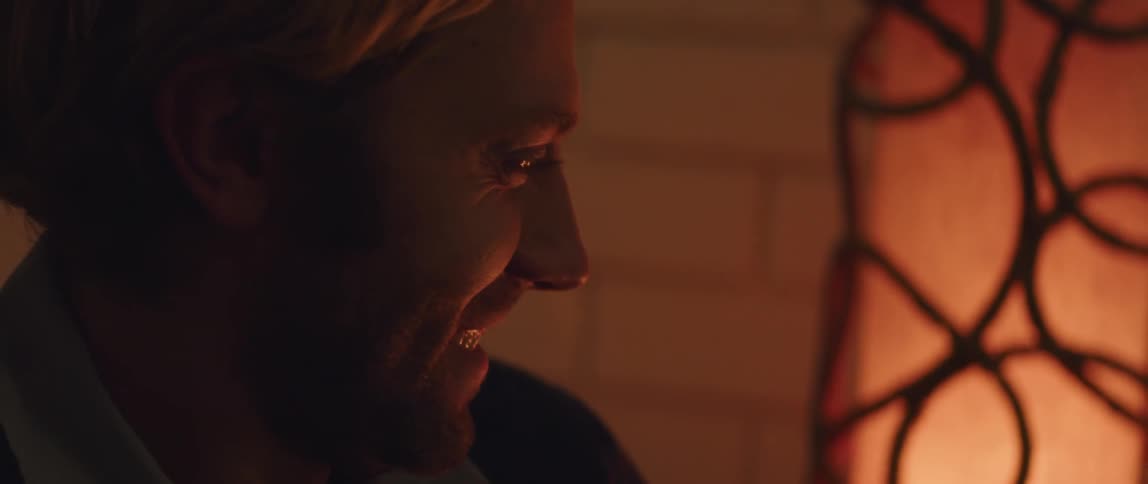 Man looks at fireplace smiling in dark room