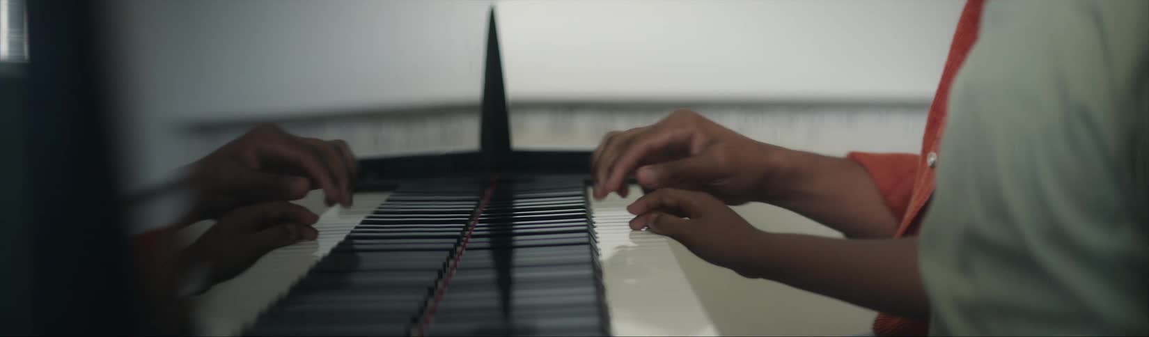 Two people playing a piano together