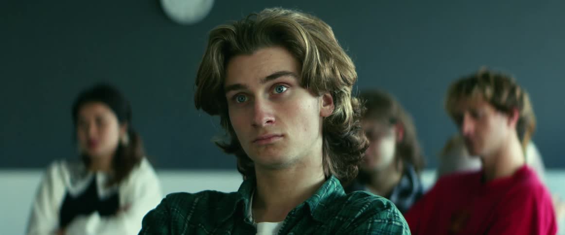 A male student sits in a classroom while listening attentively