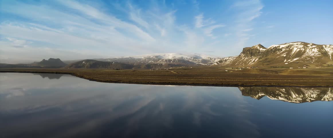 Aerial view of a snow covered mountain range reflecting on the calm clear surface of a lake