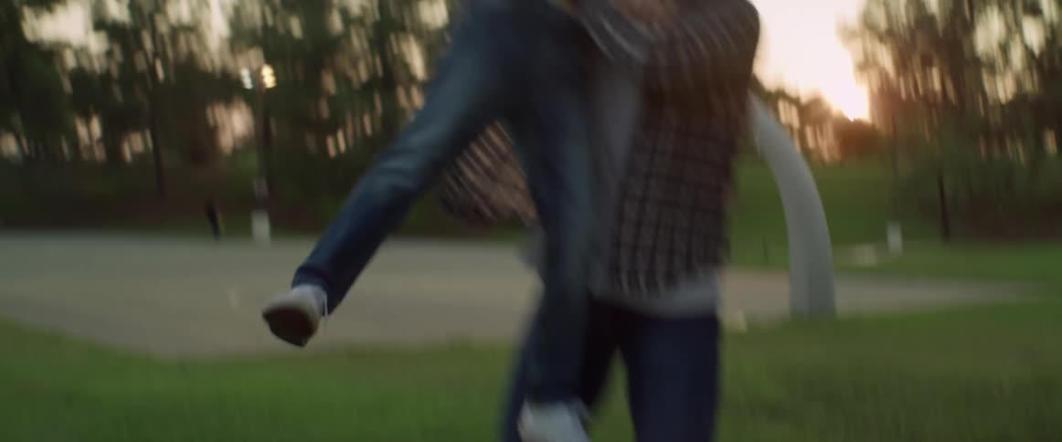 Father and son play football in the park lit by setting sun