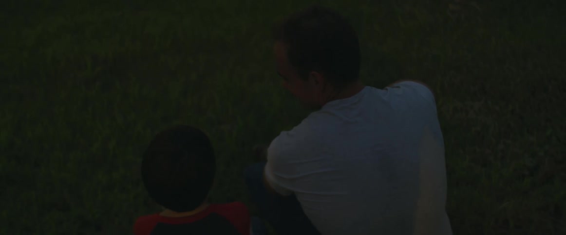 A father and son are sitting outside as flashes of light go off