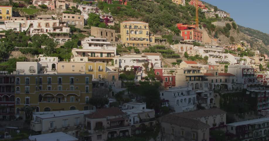 Trees border town sitting on mountain side under a clear blue sky