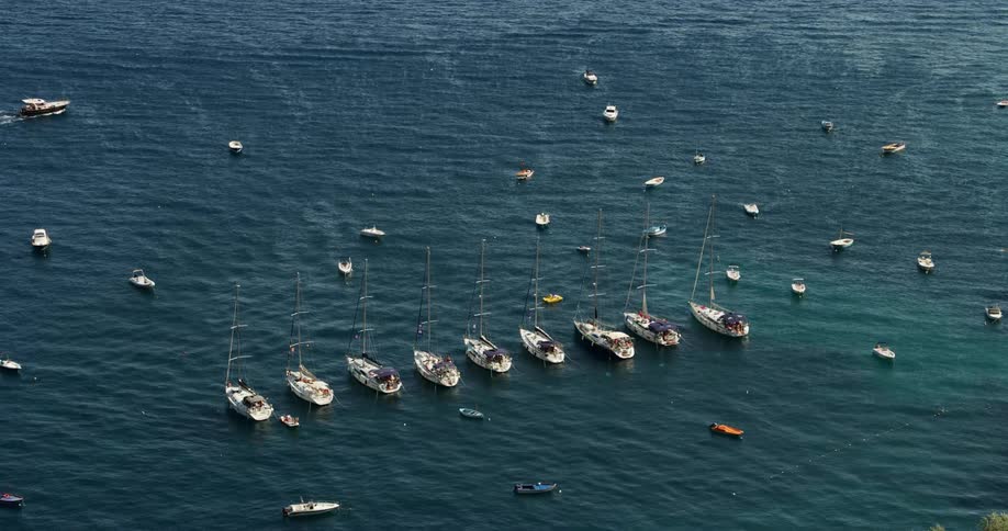 Aerial view of boats anchored in the calm blue ocean waters of a bay