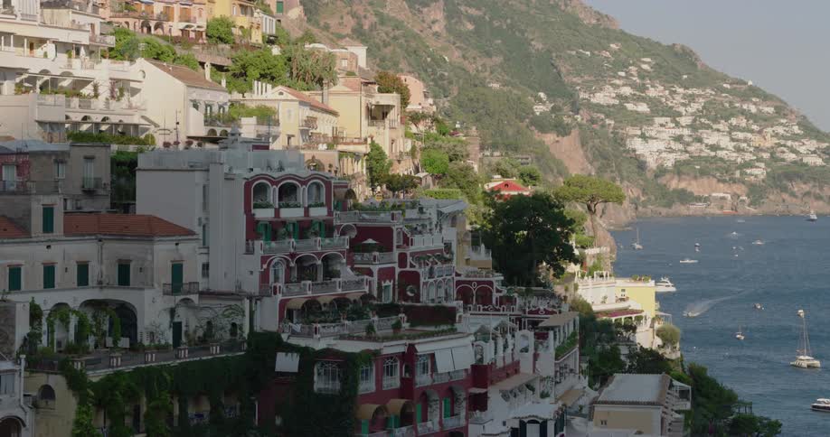 Hotels and homes built into the hill overlooking the ocean and boats along the coast