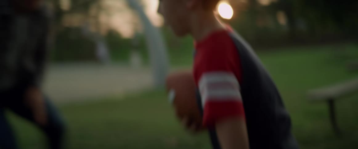 A father and son are playing football in a park