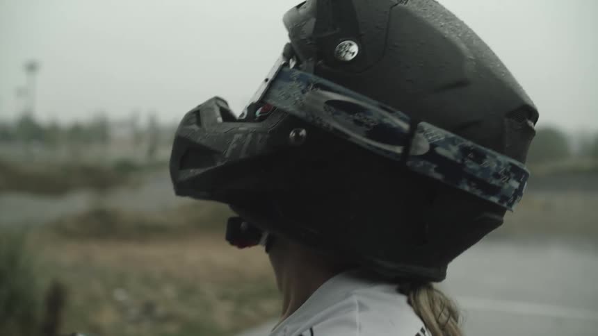 A teenage girl is riding a bike in a race in the rain