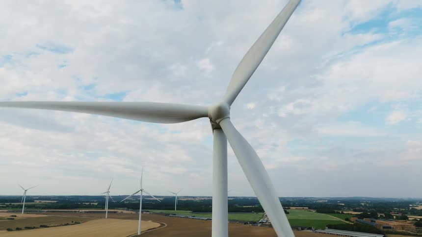 Wind turbines spin on a wind farm under a cloudy sky