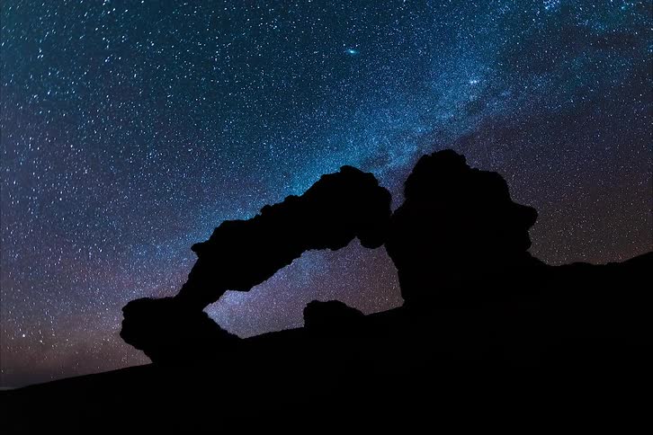 Stars above a silhouetted rock formation at night