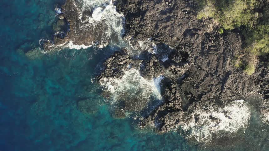 Water is crashing against the rocks on a mountainous coastline