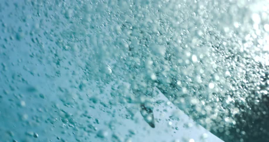 Underwater footage of a dolphin swimming through air bubbles rising to the surface of the ocean