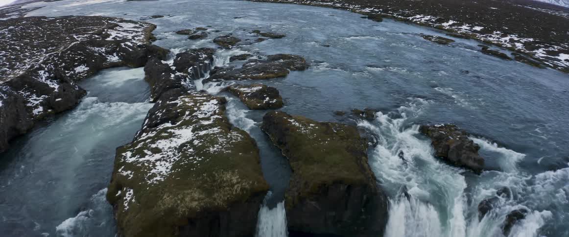 Aerial view of a glacier waterfall next to the mountains at evening