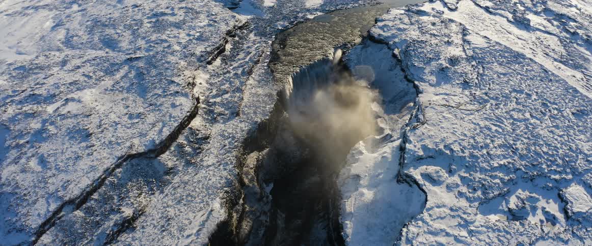 A river flows into a canyon in a frozen countryside during the day