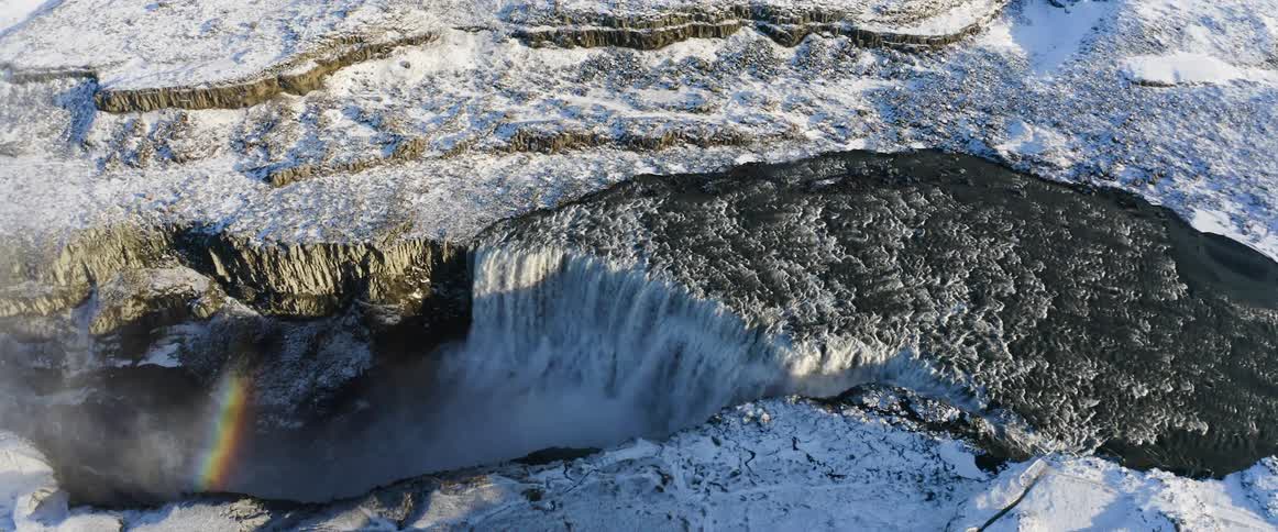 Camera slowly turns above a river going into a large waterfall