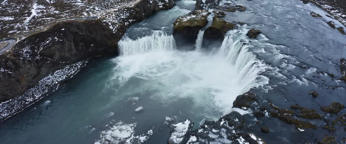 An aerial view of a river flowing over a cliff in winter