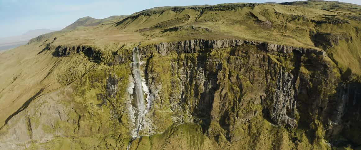 Aerial view of a waterfall on the side of a mountain at daytime
