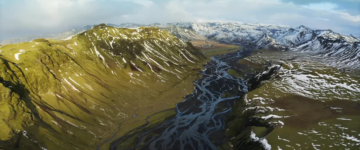 An aerial view of rivers flowing through snowy mountains in winter