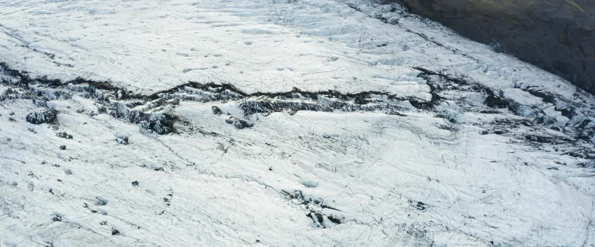 Aerial view of a crack in the snow covered terrain on a mountainside