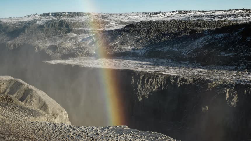 Steam rising from a canyon with a rainbow on a winter day