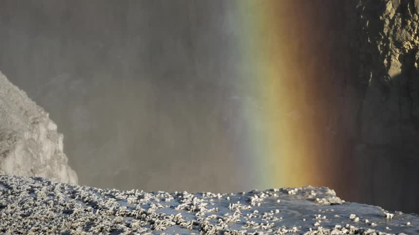 Mist and a rainbow in a snowy canyon