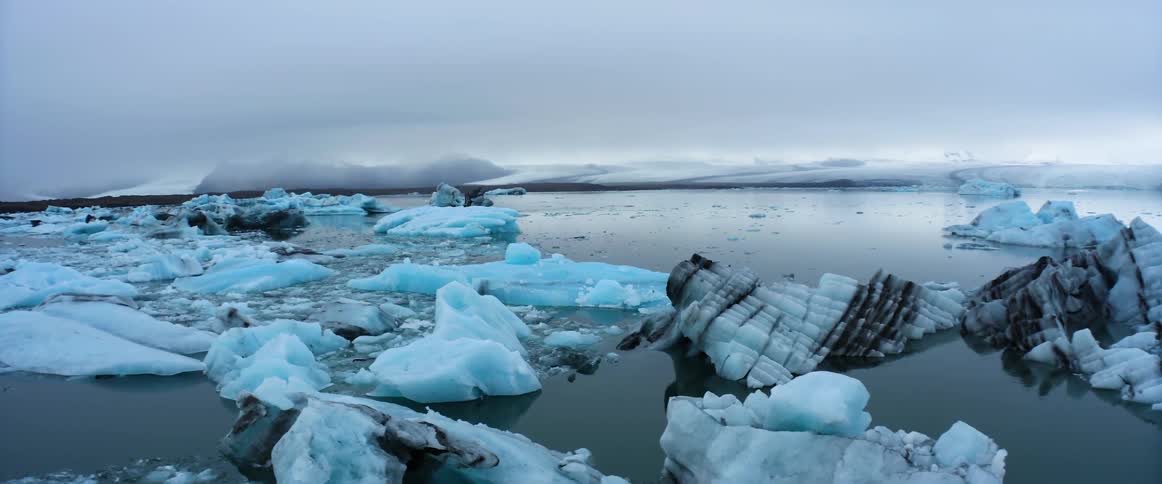 Sea ice some dirty floats on reflective water stretching to the horizon