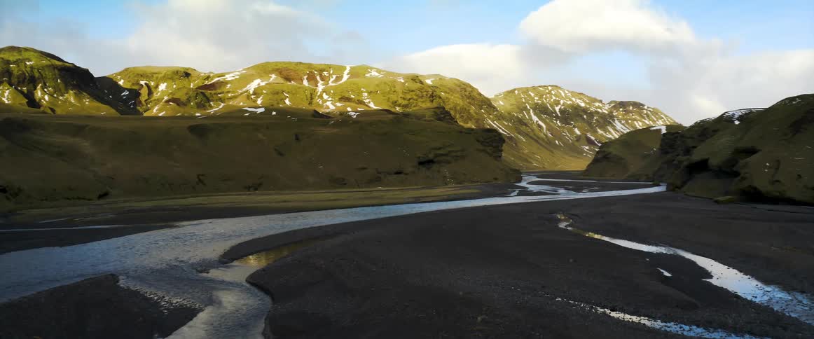 A river flowing through mountains with snow in the daytime